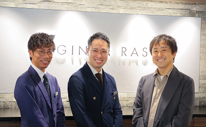 クライアントと担当者が企業ロゴの前で笑顔で並ぶ