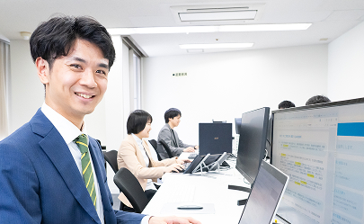 オフィスのデスクでパソコン作業をするスーツ姿の男性社員