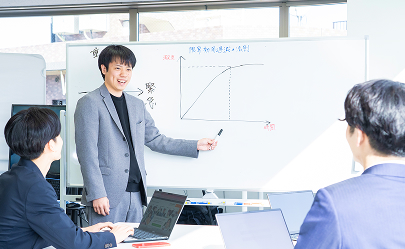 ホワイトボードを使って説明する男性社員とスタッフ